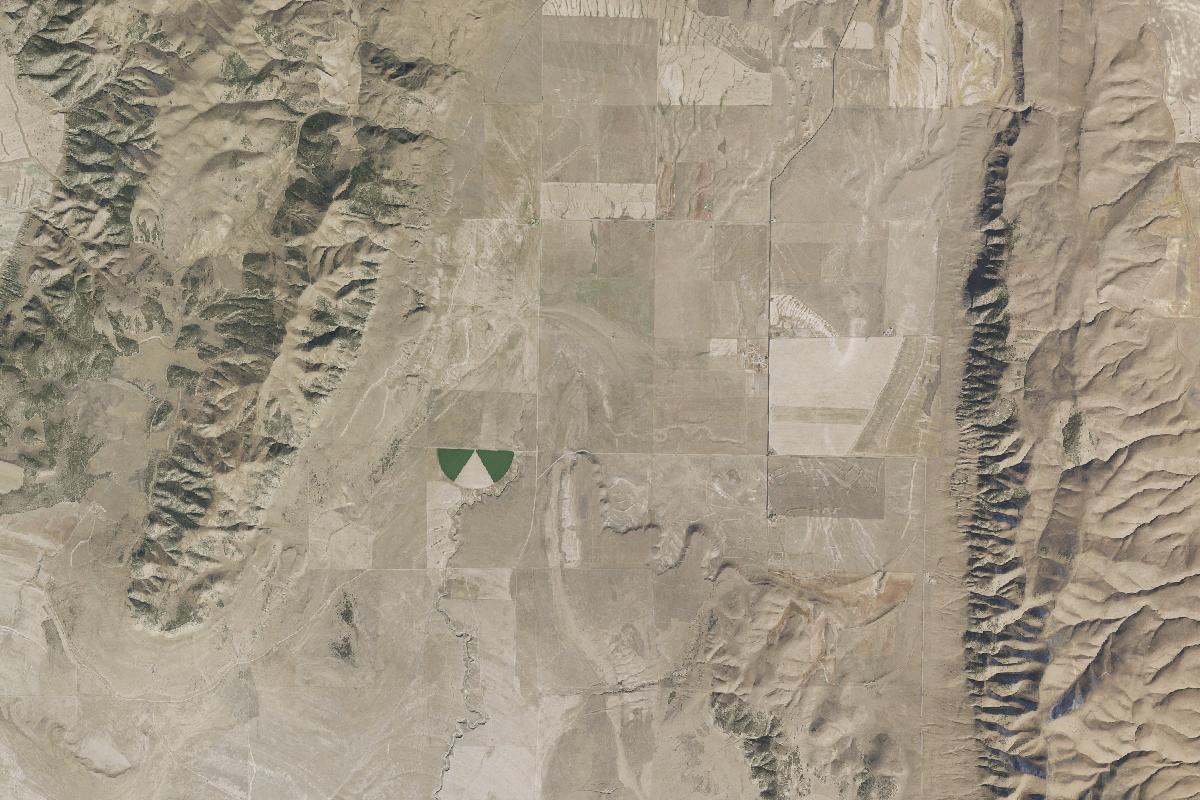 Aerial view of Hansel Valley in Box Elder County: a dry valley floor of dryland fields between two ranges, one irrigated circle at its centre.